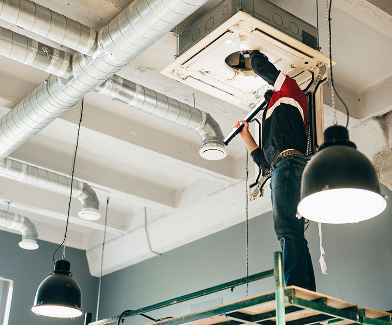 Engineer servicing ceiling mounted air conditioning unit