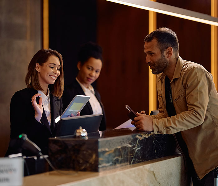 hotel staff at reception dealing with a happy guest