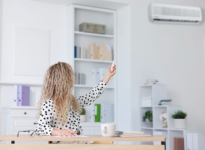 woman operating air con in her office